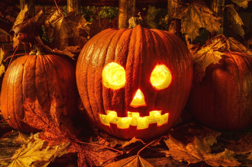 Jack-o'-lantern among autumn leaves