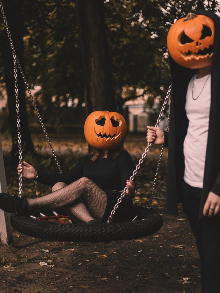People in pumpkin masks on a swing