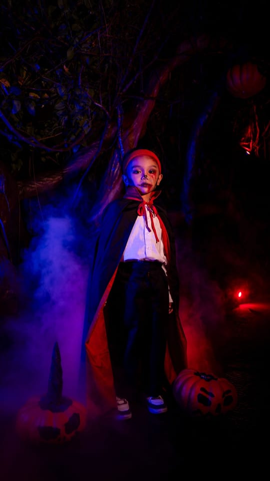 Child in vampire costume with pumpkins
