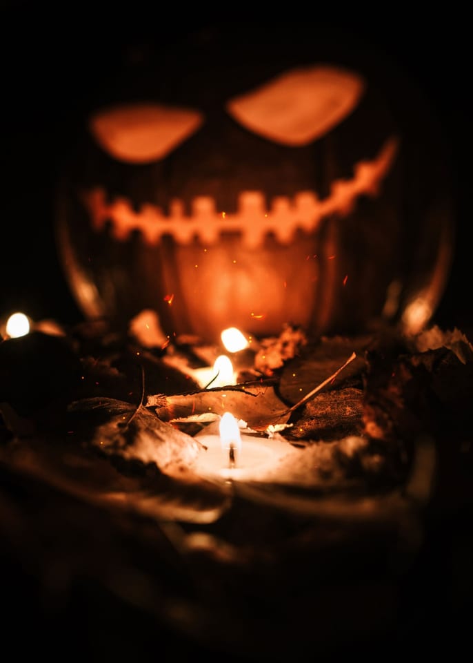 Creepy jack-o'-lantern in fallen leaves
